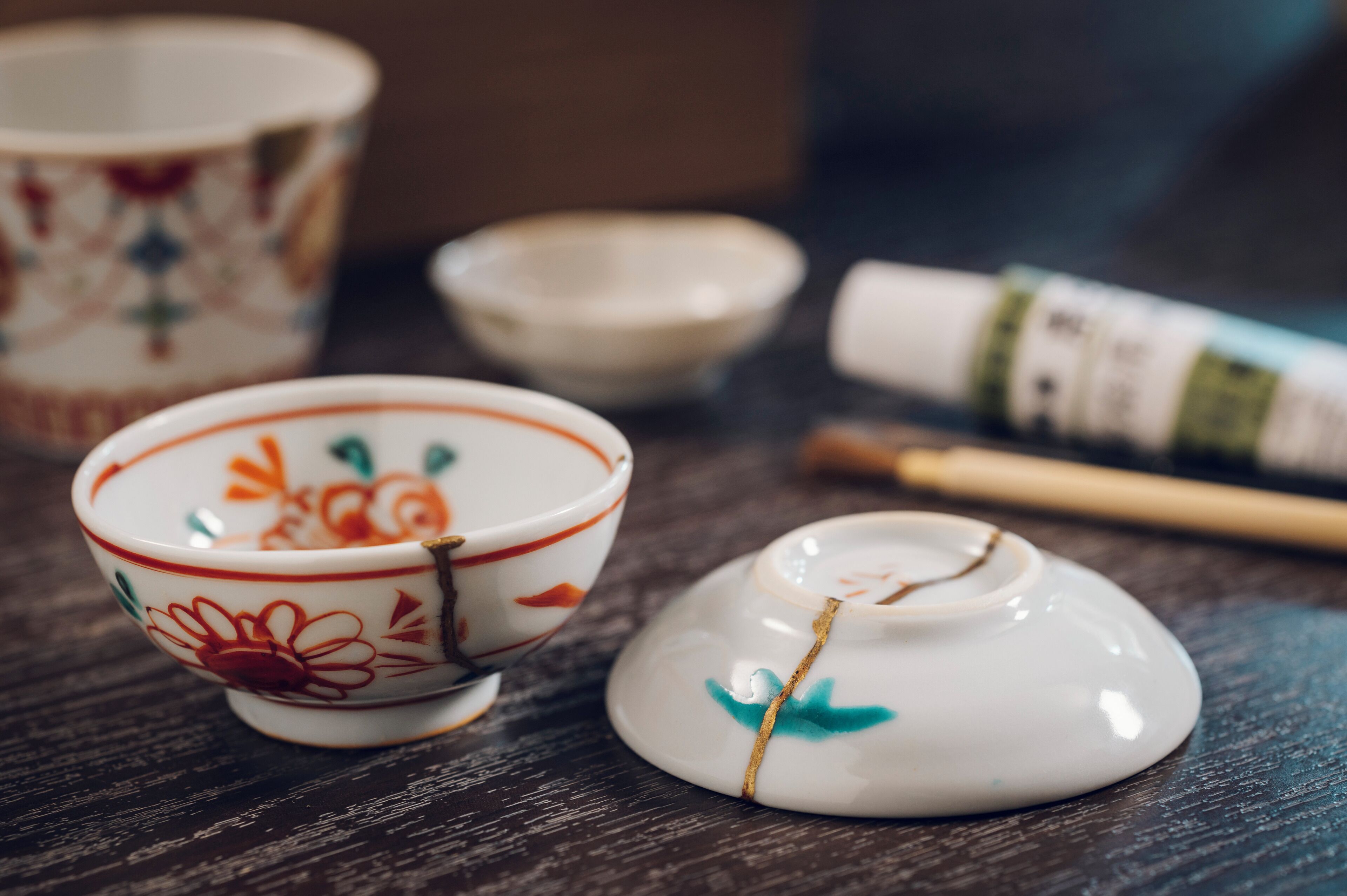 A set of ceramic tea cups and a small teapot on a wooden table.