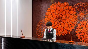 A reception desk with a large, colorful floral mosaic wall behind it.