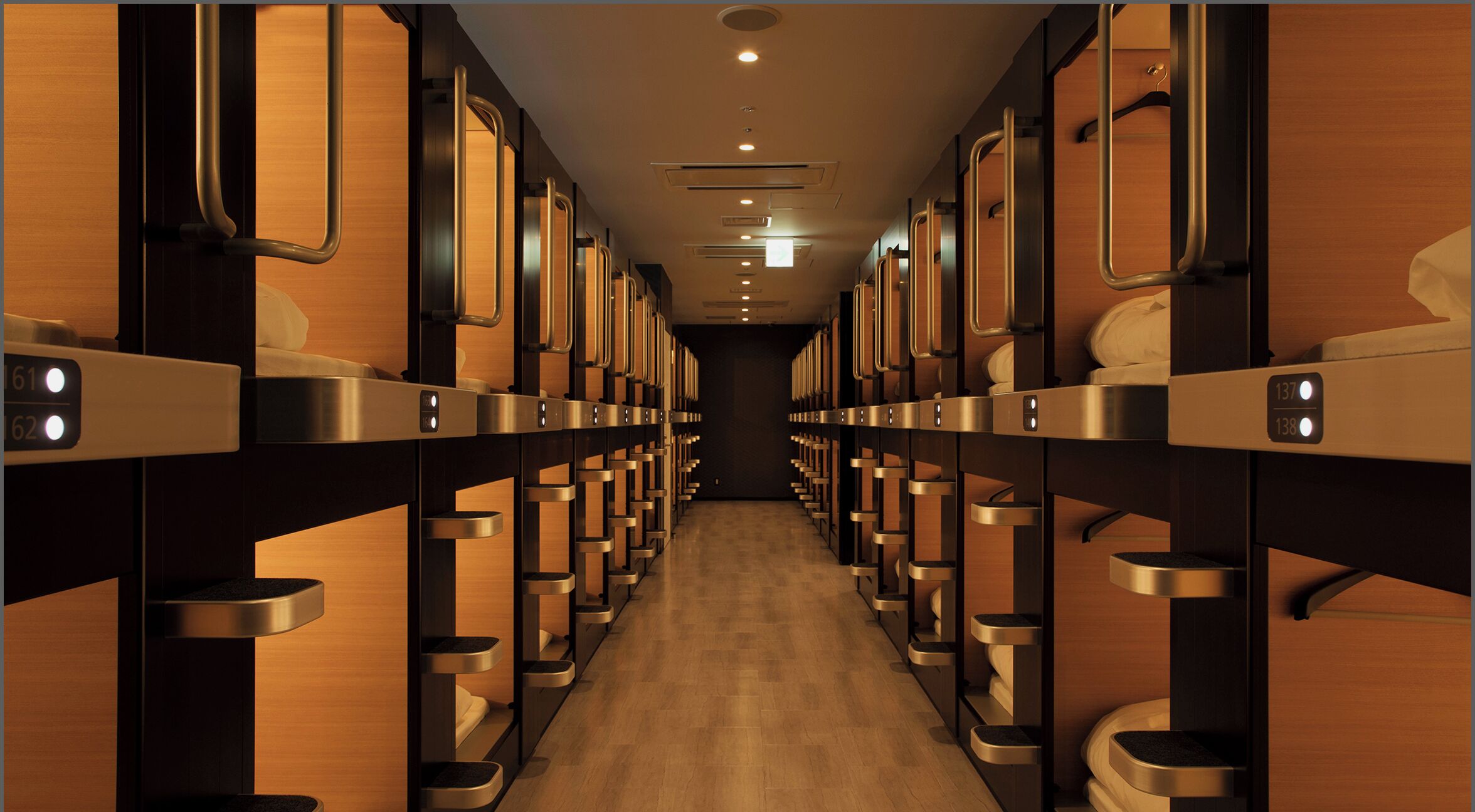A row of bunk beds with individual compartments, each with a small shelf and a light.