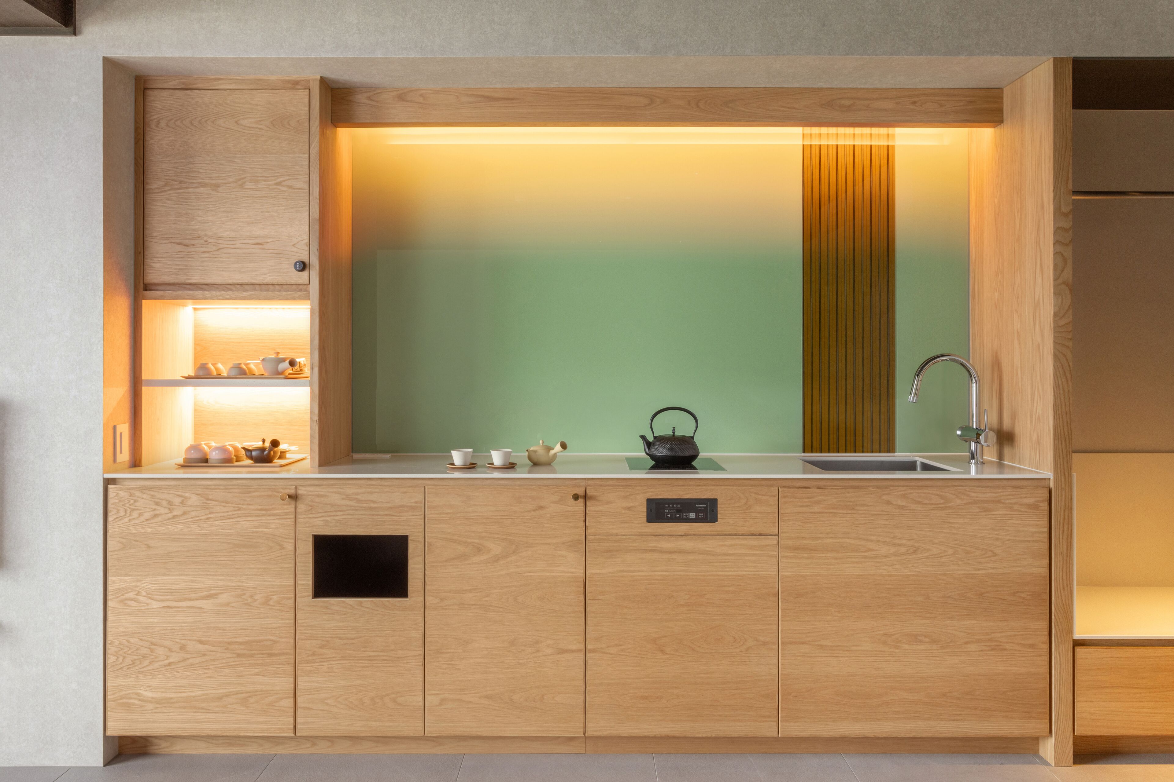 Una cocina moderna con armarios de madera, un lavaplatos empotrado y un salpicadero verde.