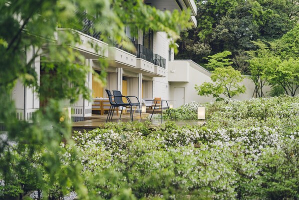 Een modern gebouw met een balkon, buitenmeubilair en weelderige beplanting.