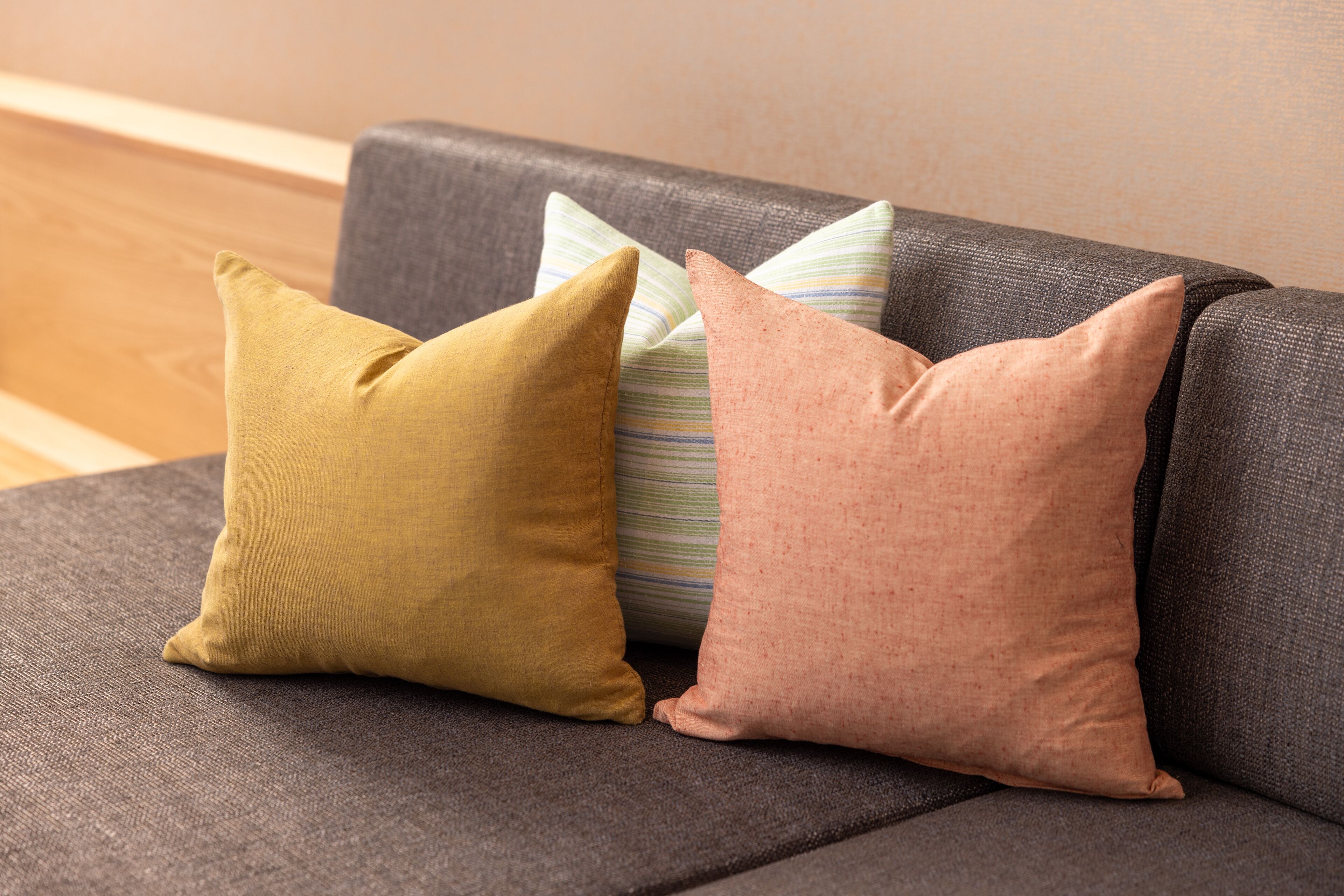 A gray sofa with three pillows in different colors.