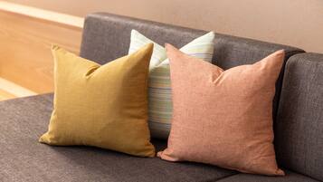 A gray sofa with three pillows in different colors.