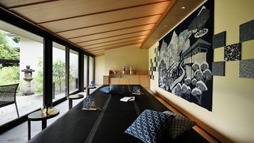 A modern room with a long bed, a small table, and a large wall with various black and white patterns.