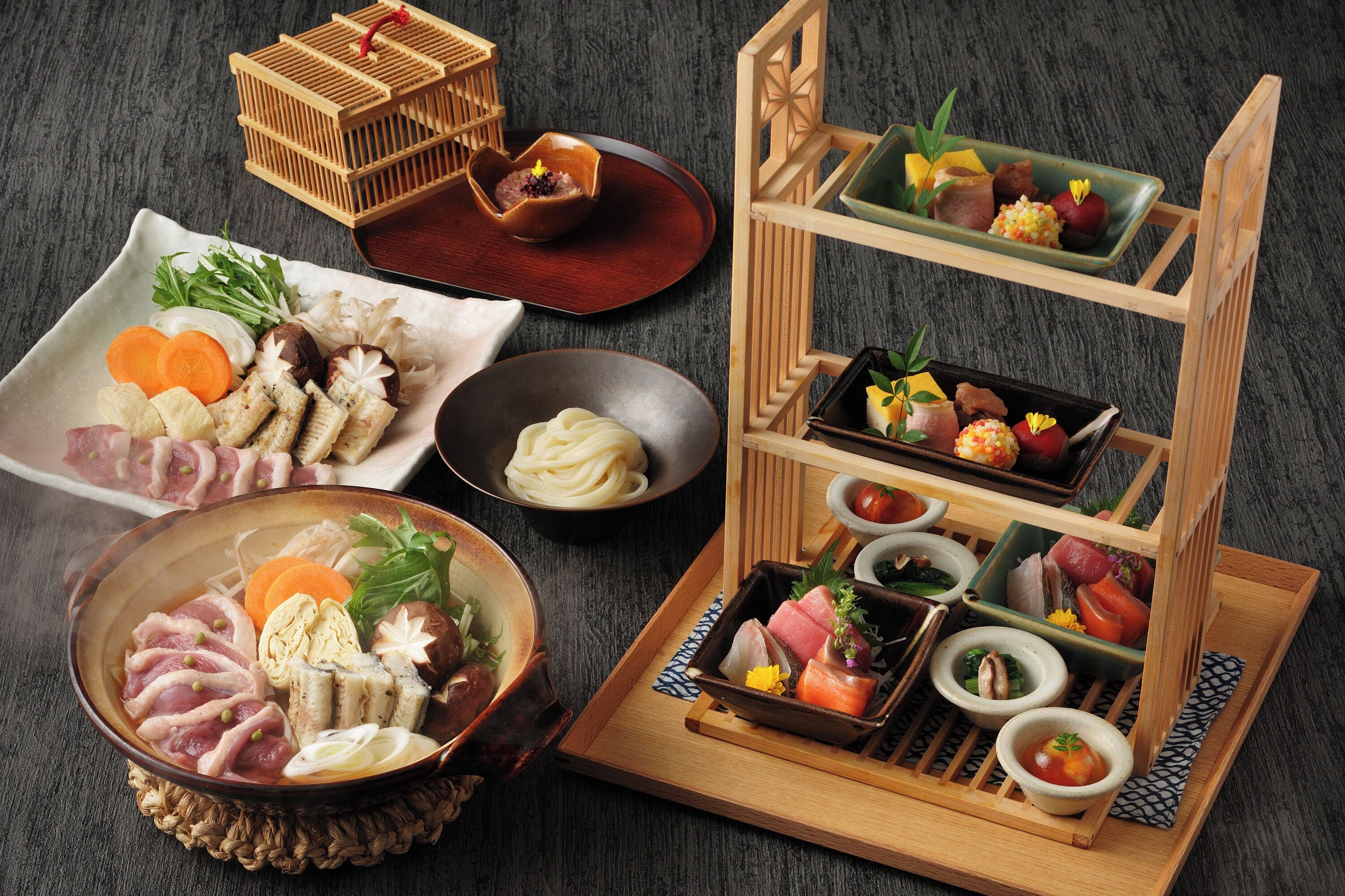 A traditional Japanese meal setup with various dishes and a wooden stand displaying different food items.