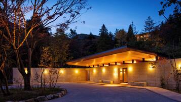 A modern building with a flat roof, large windows, and a paved entrance area.