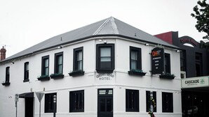 A white building with black-framed windows and a sign reading "Queens Head Hotel." - Queens Head Hotel (North Hobart)