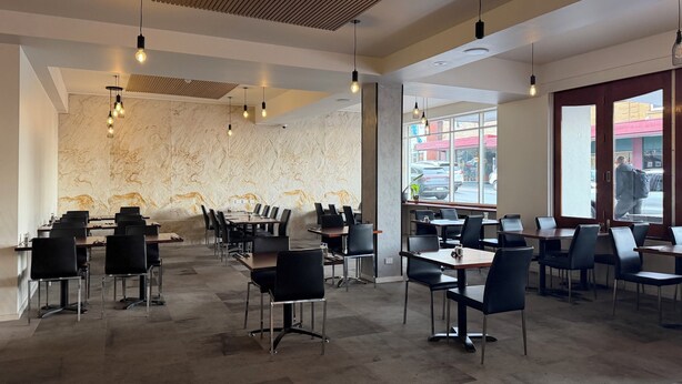 A modern restaurant interior with marble walls, black chairs, and pendant lighting. - Queens Head Hotel (North Hobart)