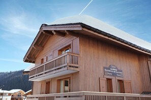 A wooden building with a balcony, a sign indicating it is a residence de tourisme, and a ski slope in the background. - Apartment in Le Village Complex, France (Notre Dame de Bellecombe)
