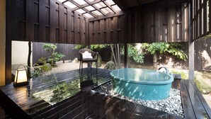 Una terraza de madera con un jacuzzi, una silla y un farol.