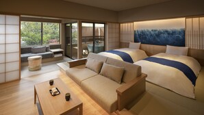 Una habitación de hotel moderna con sofá, dos camas, una mesita de madera y vistas al balcón exterior por una puerta corredera.