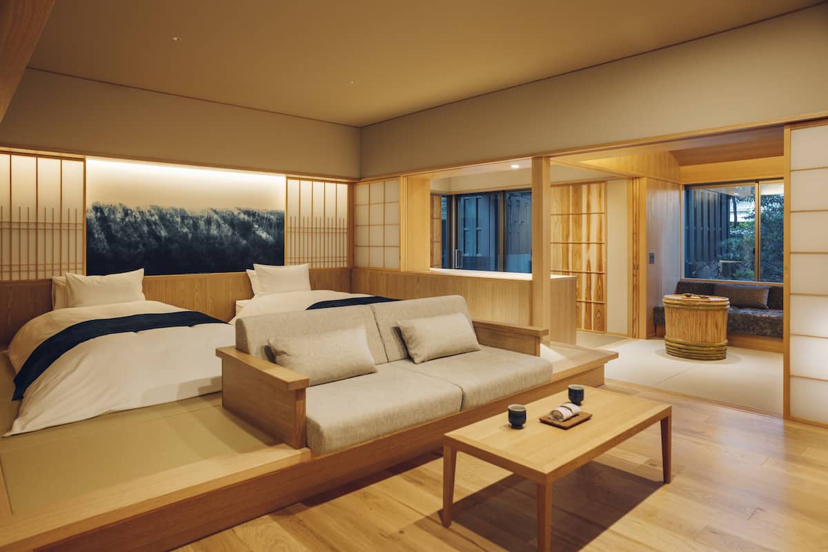 Une chambre à coucher moderne et minimaliste, avec un grand lit, un canapé et une table basse en bois.