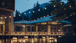 Un edificio moderno con fachada de vidrio, zona de estar al aire libre y luces colgantes.