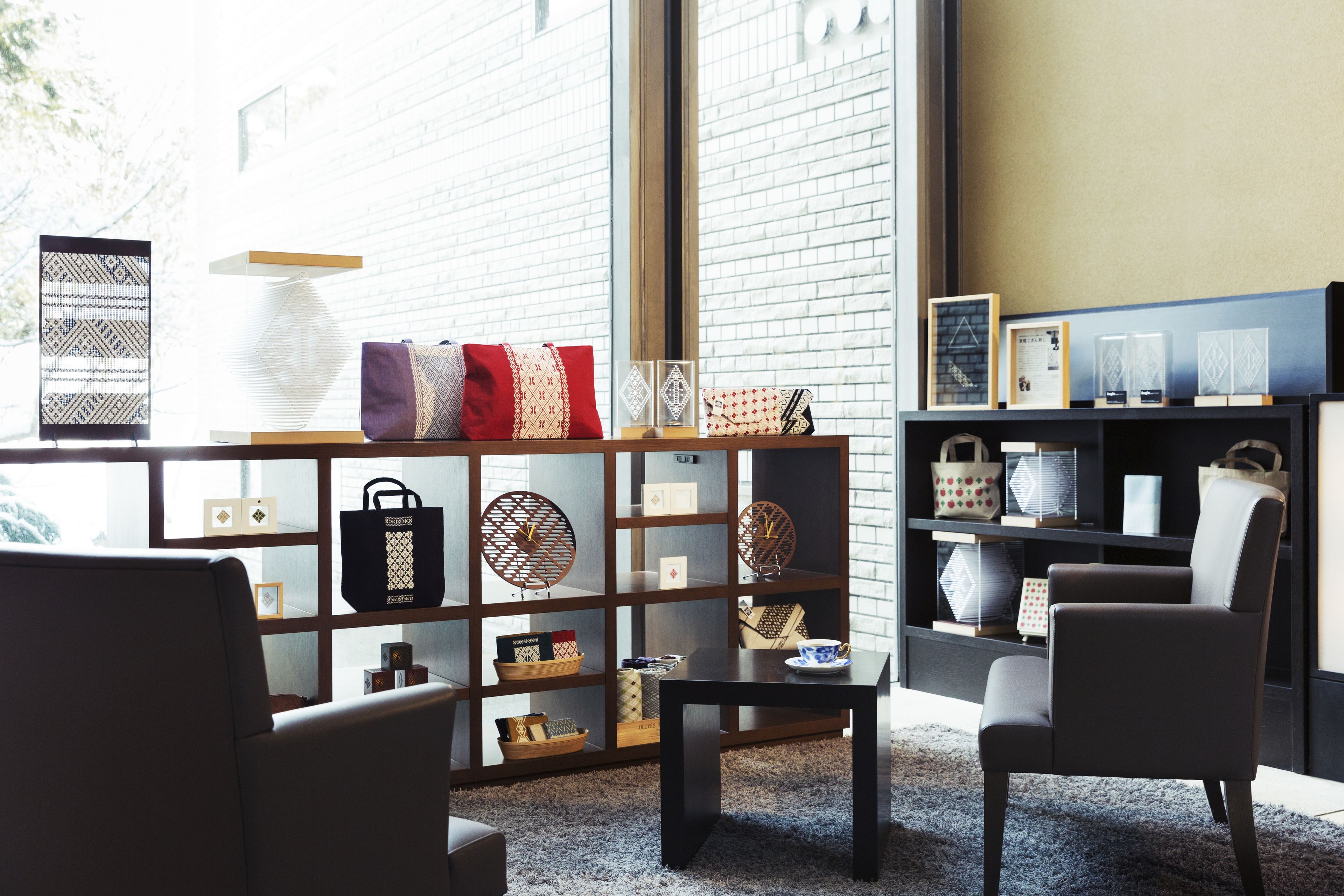 A modern living room with a sofa, armchairs, a coffee table, and a bookshelf filled with decorative items and books.