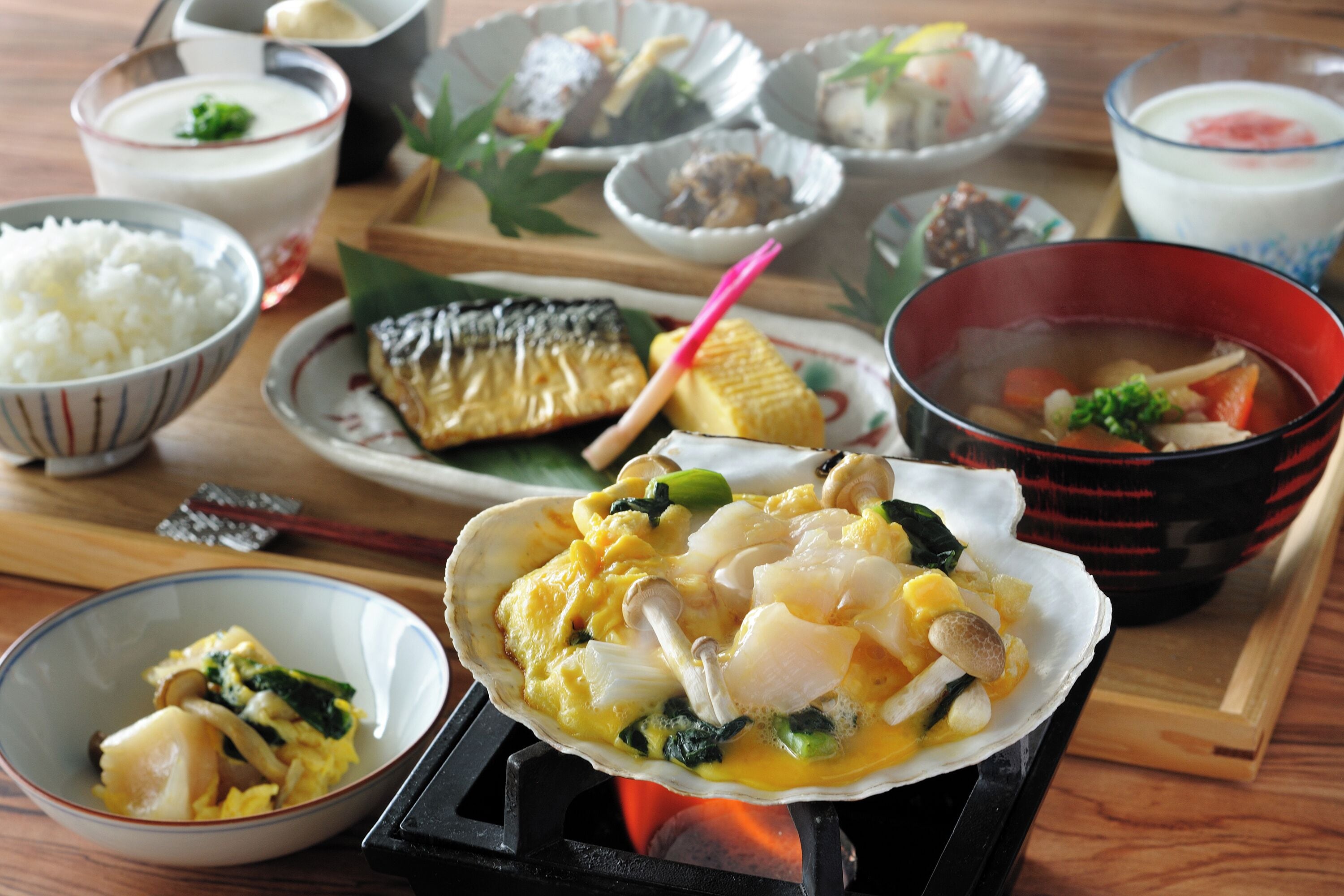A variety of dishes including a bowl of rice, a plate with fish, and a bowl of soup.