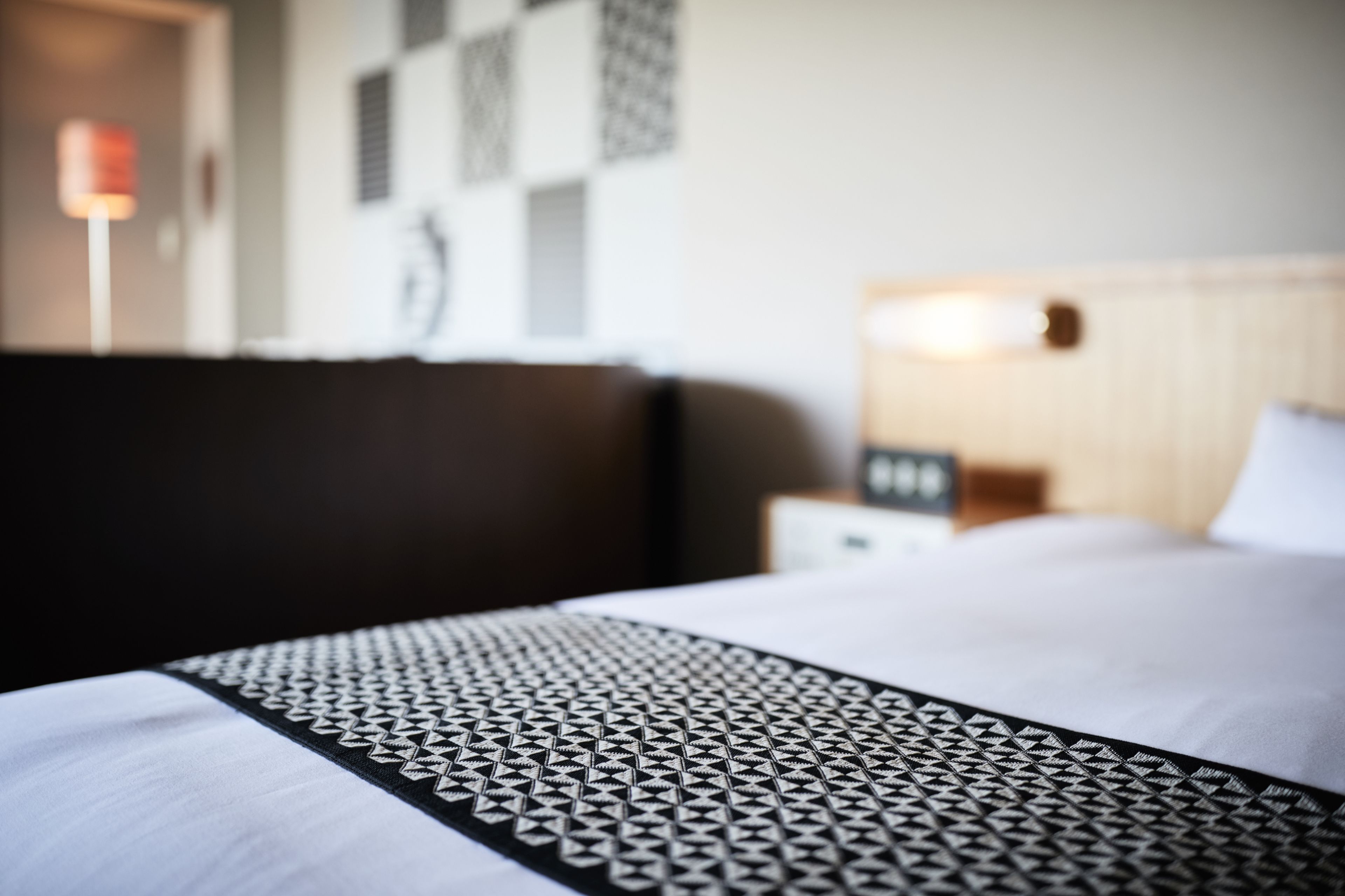 Una habitación de hotel con una cama bien hecha, cabecera y una pared decorada con diseños.