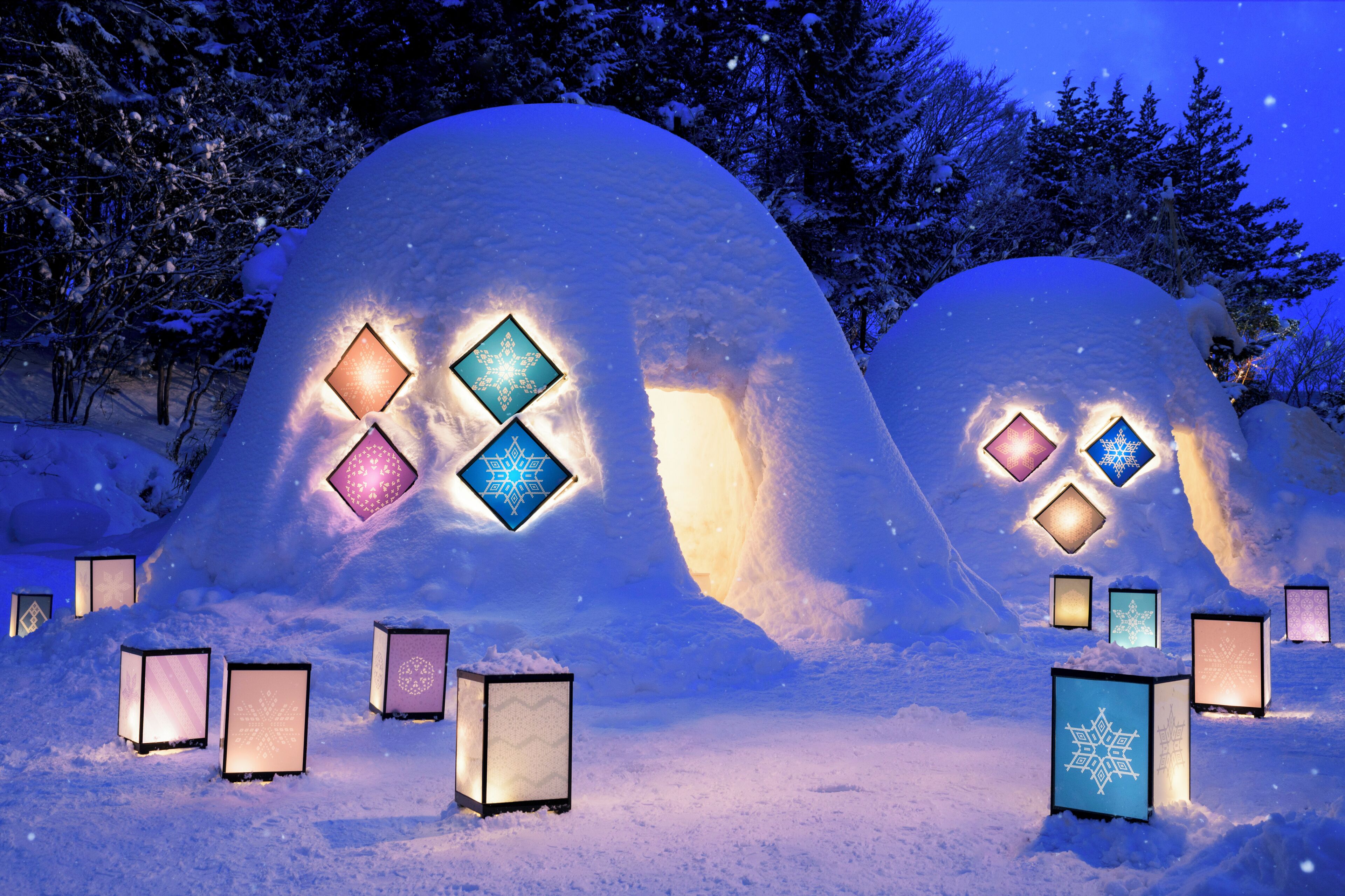 Igloos cobertes de neu amb finestres il·luminades.