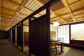 Una habitación japonesa tradicional con suelo de tatami, puertas correderas y una mesa baja con sillas.