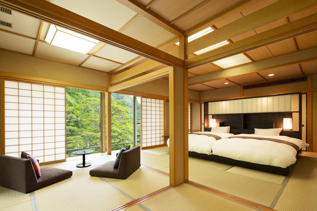 A traditional Japanese-style bedroom with tatami flooring, a large bed, and sliding shoji doors.