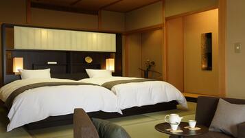 A hotel room with two beds, a sofa, a small table with cups, and a decorative vase.