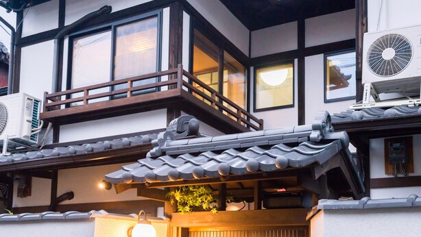 Un bâtiment traditionnel japonais doté d’un balcon en bois, de grands éventails et d’un toit recouvert de tuiles.