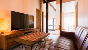 Un salon moderne doté d’un téléviseur à écran plat, de meubles en bois et d’un canapé en cuir.