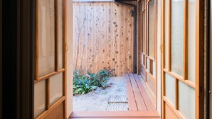 Un couloir intérieur en bois, avec un plancher en bois et une vue sur un jardin.
