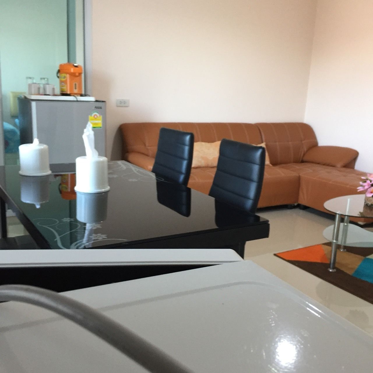 A modern living room with a glass coffee table, a sofa, and a dining table with chairs.