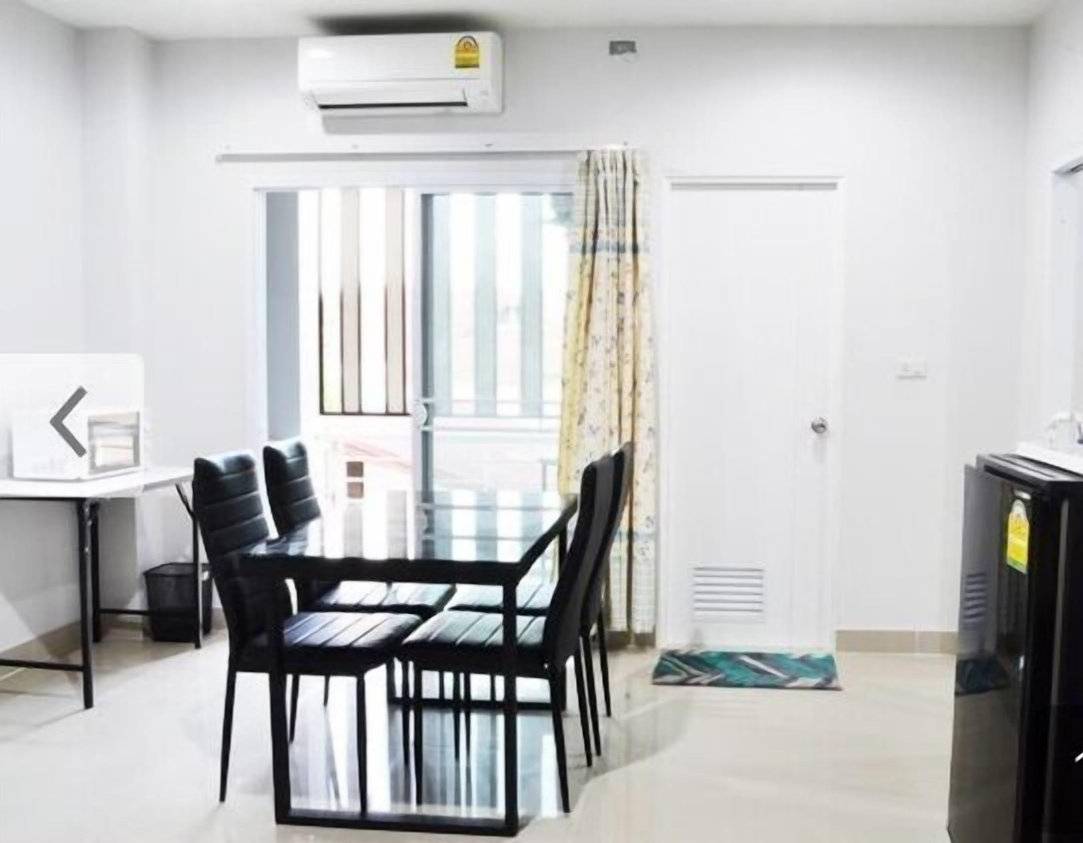 Un apartamento moderno con zona de comedor, kitchenette y un gran ventanal con cortinas.