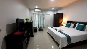 A hotel room with a bed, a desk, a television, an air conditioning unit, and a window with curtains.