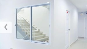 A modern interior with a staircase, a glass door, and a white wall.
