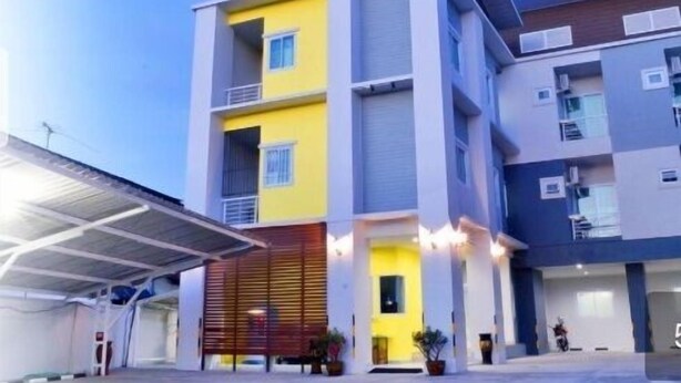 A multi-story building with a modern architectural design, featuring balconies and a covered entrance area.
