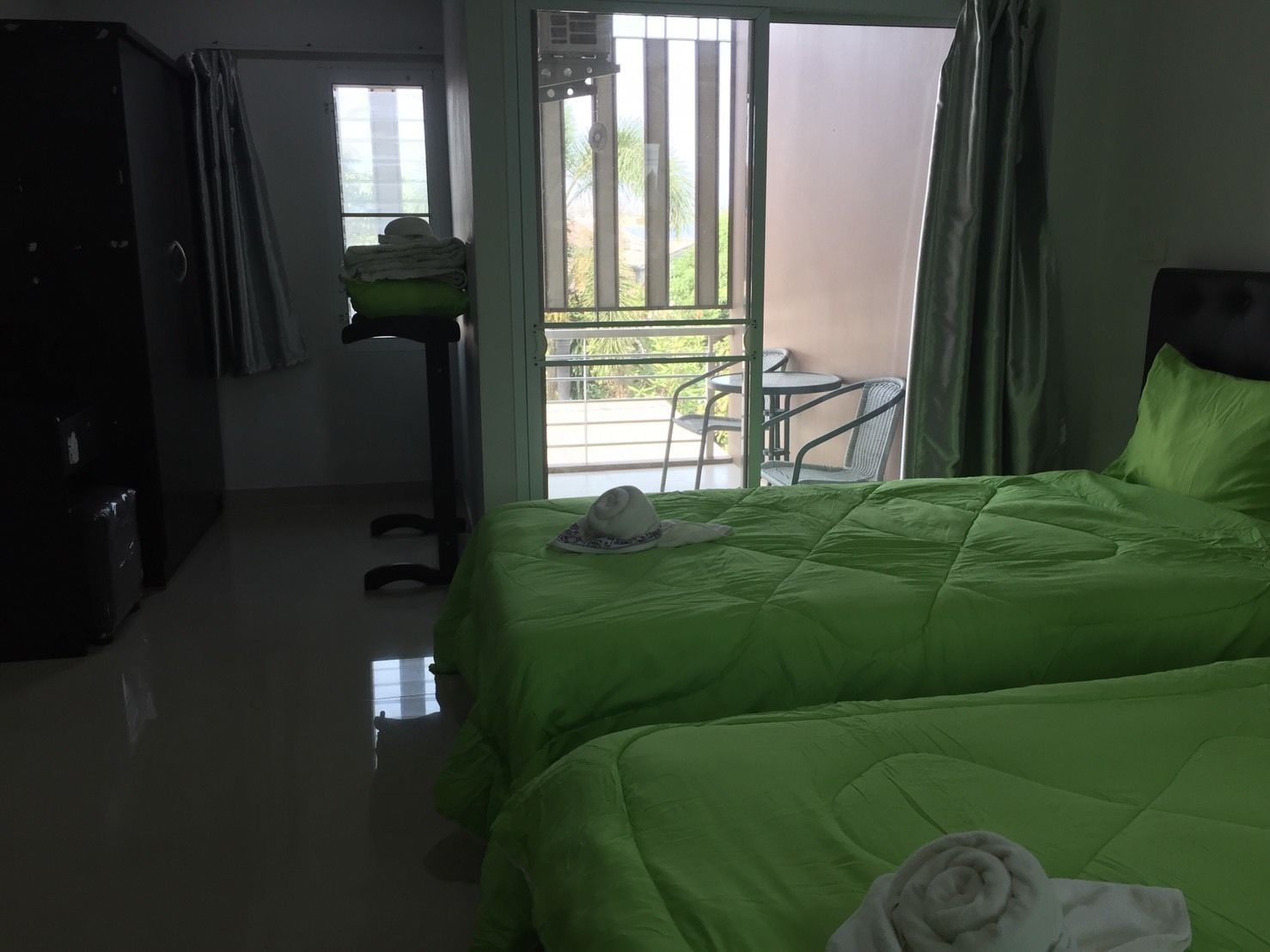 A hotel room with two beds, a balcony with a table and chairs, and a wardrobe.