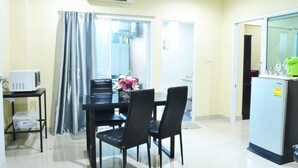 A compact kitchen with a refrigerator, microwave, and dining table with chairs.