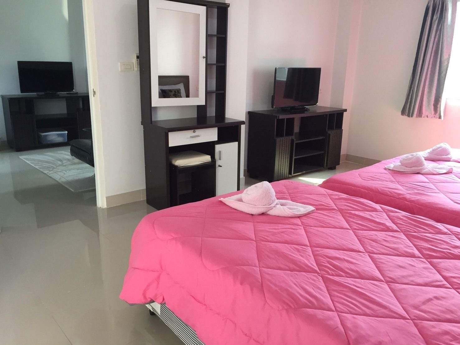 A hotel room with two beds, a TV, a wardrobe, and a desk.