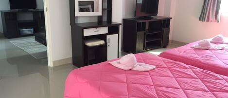 A hotel room with two beds, a TV, a wardrobe, and a desk.
