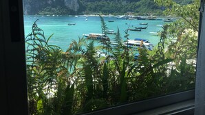 A coastal view with boats, greenery, and mountains. - Coco's Guesthouse (Ko Phi Phi)
