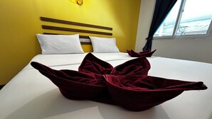 A hotel room with a bed, white bedding, and a view of the sea through a window. - Coco's Guesthouse (Ko Phi Phi)