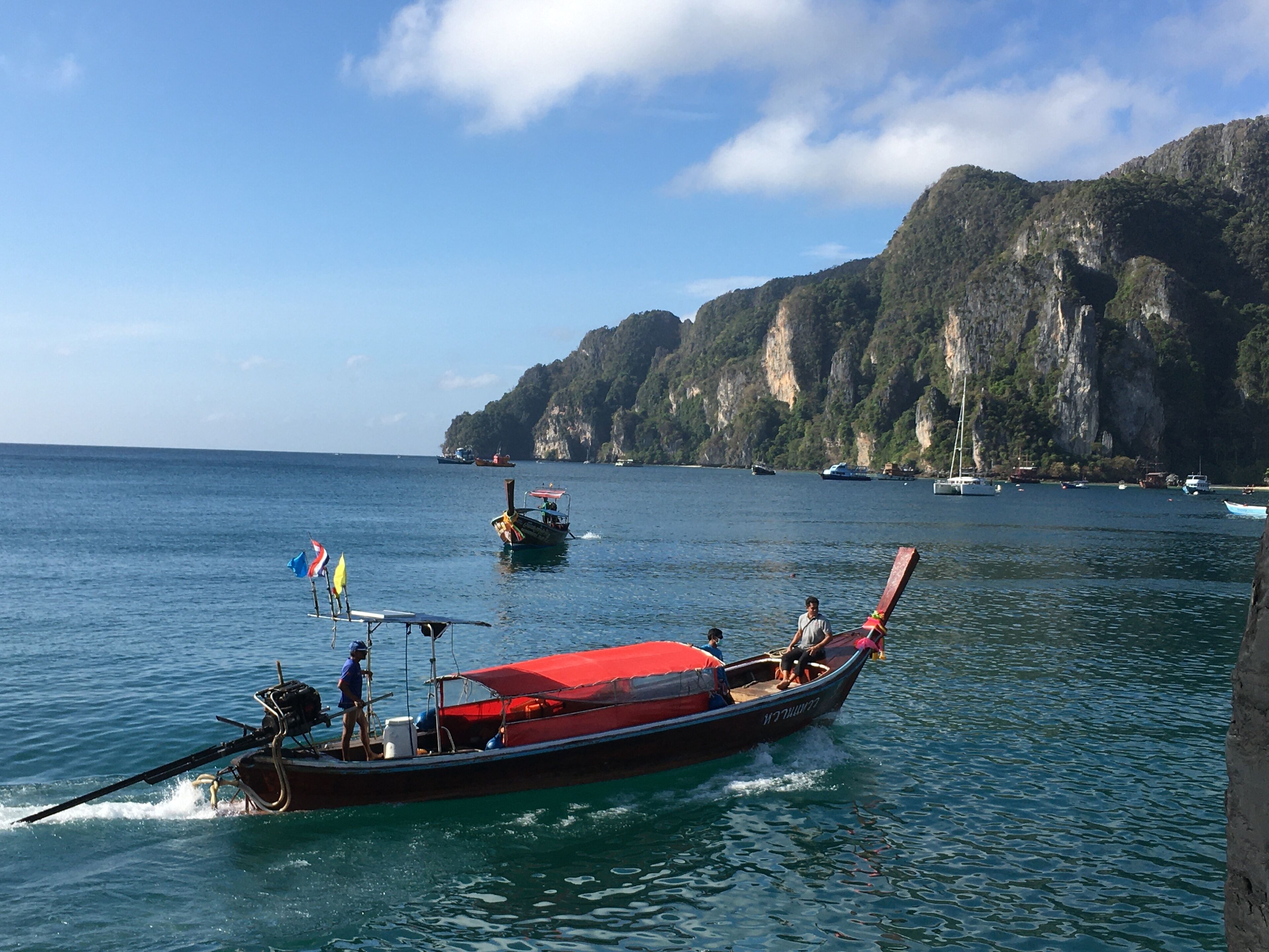 A traditional long-tail boat on calm waters with a mountainous backdrop.