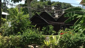 A building with multiple floors and balconies, surrounded by dense greenery and a concrete wall. - Coco's Guesthouse (Ko Phi Phi)