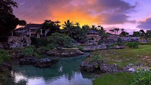 A tropical resort with a water feature, palm trees, and a sunset view. - Tanna Evergreen Resort & Tours (Tanna Island)