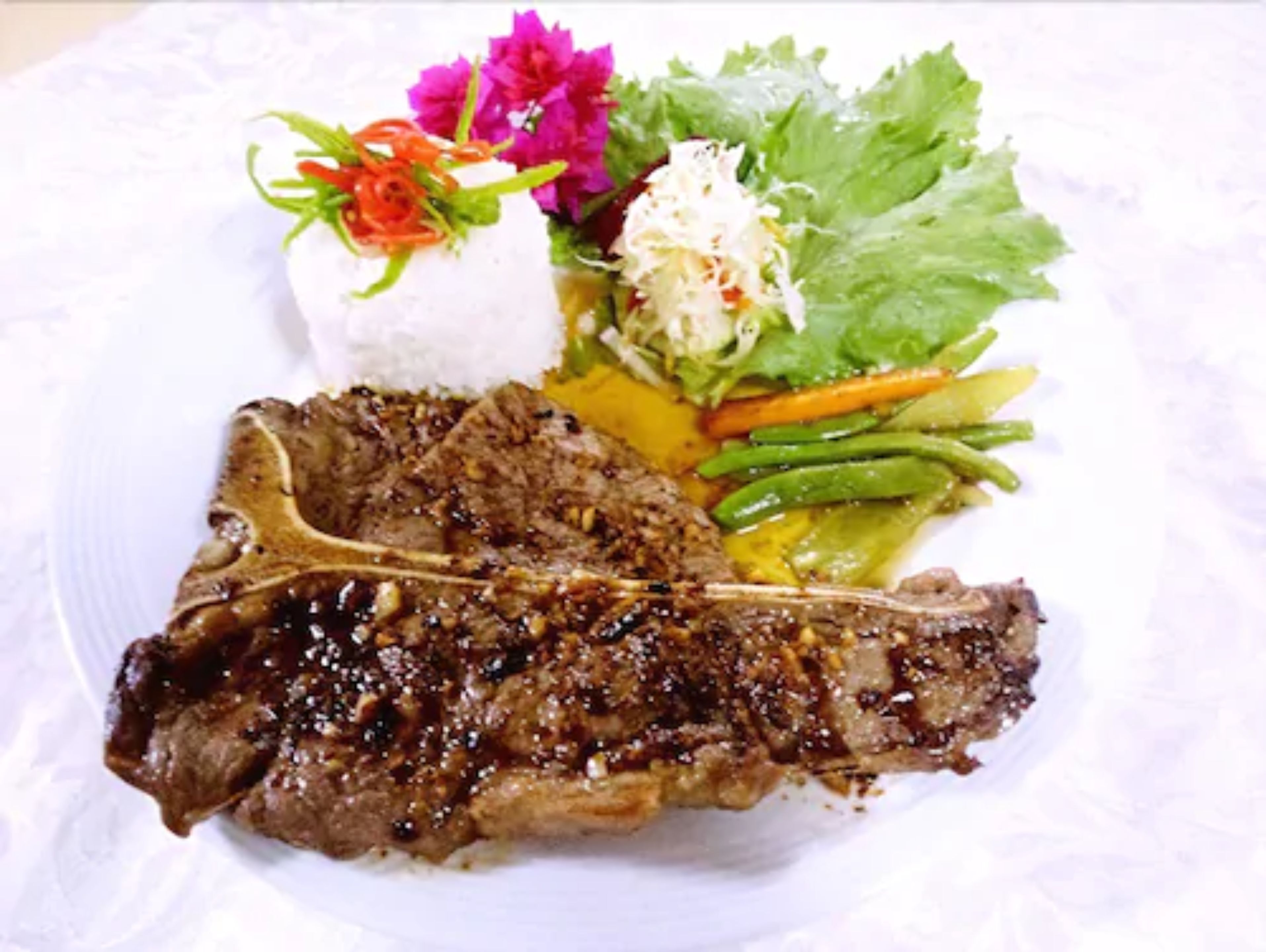 Un plato con un filete a la parrilla, una ensalada y una porción pequeña de arroz.