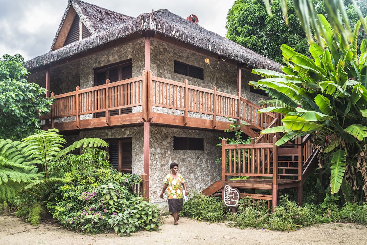 A two-story stone house with a thatched roof and wooden balcony.