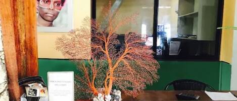 Una mesa de recepción con un cuadro enmarcado, una planta decorativa y un cartel.