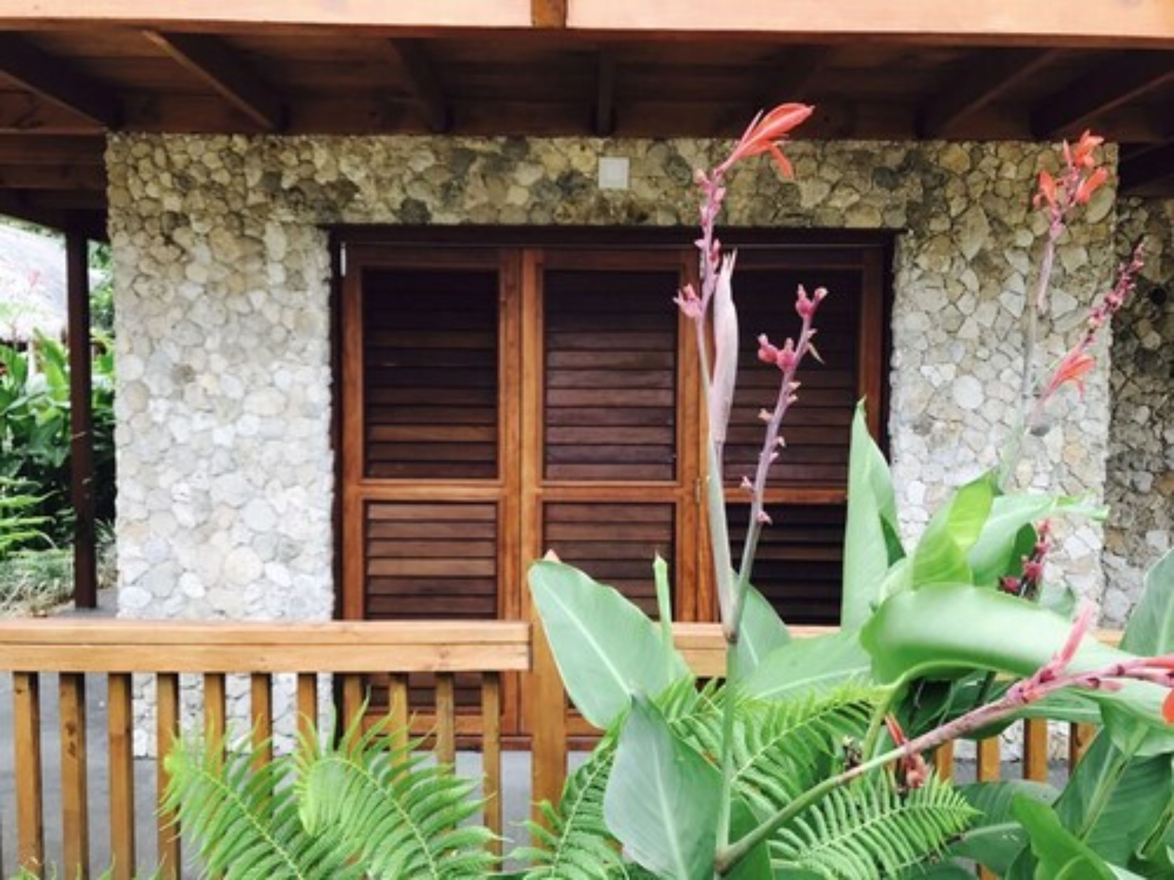 Un edificio de piedra con contraventanas de madera y una terraza de madera.