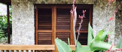 Un edificio de piedra con contraventanas de madera y una terraza de madera.