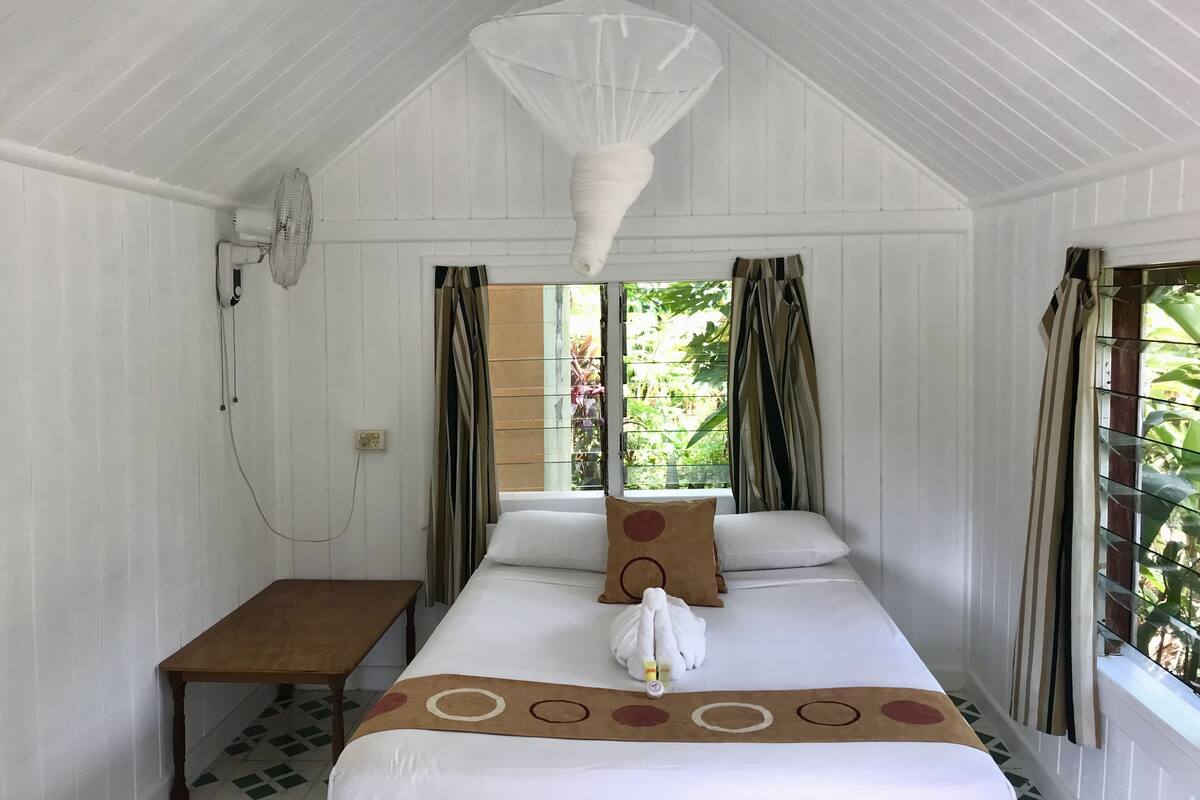 A room with a bed, a table, and a hanging light fixture.