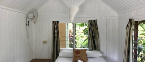 A room with a bed, a table, and a hanging light fixture.