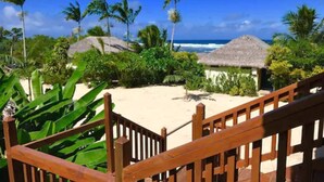 A wooden staircase leading to a beach area with thatched-roof huts and palm trees. - Tanna Evergreen Resort & Tours (Tanna Island)