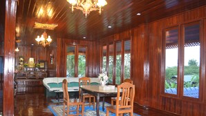 Una habitación amplia con piso de madera, una mesa de comedor con sillas, un sofá y un candelabro.